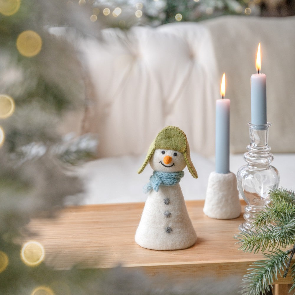 Een sneeuwpop met een groene muts en een blauwe sjaal gemaakt van wolvilt.