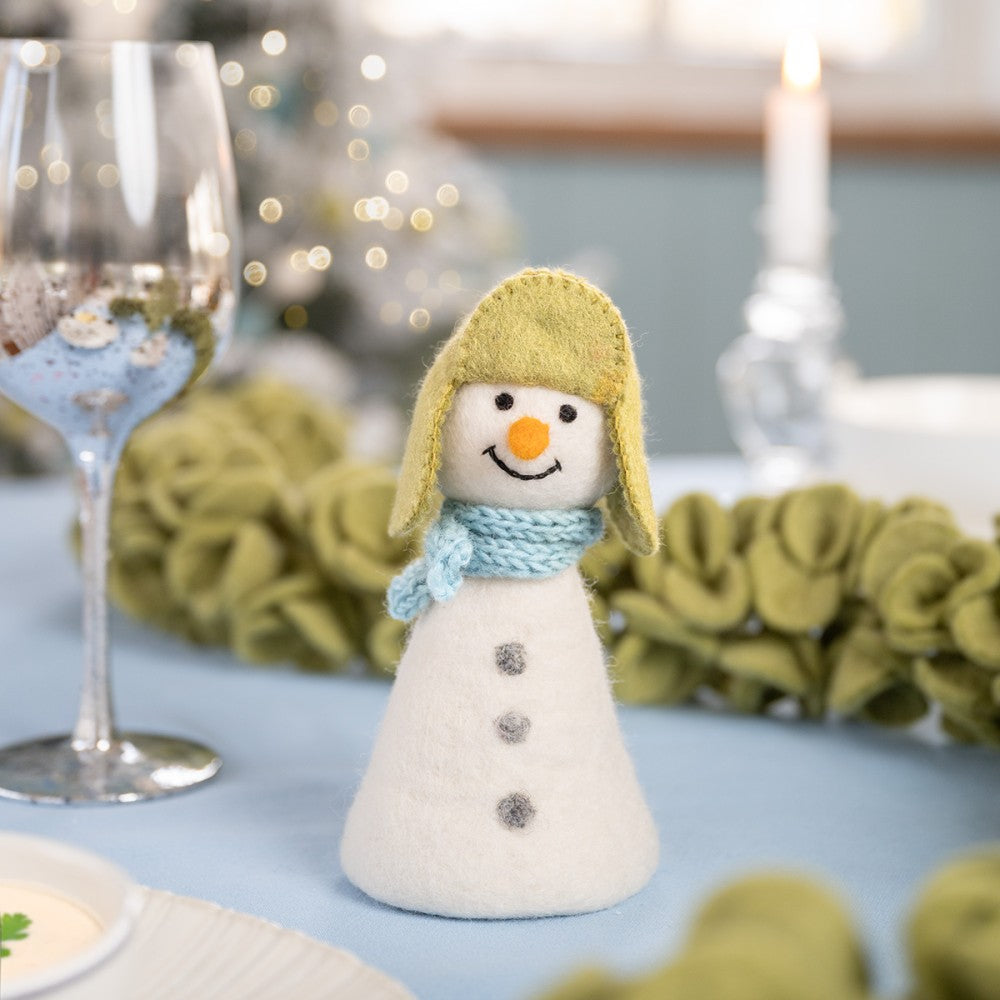 Een sneeuwpop met een groene muts en een blauwe sjaal gemaakt van wolvilt.