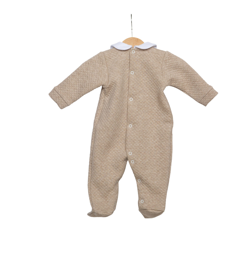 Een beige boxpakje met een wit kraagje aan een kledinghaakje