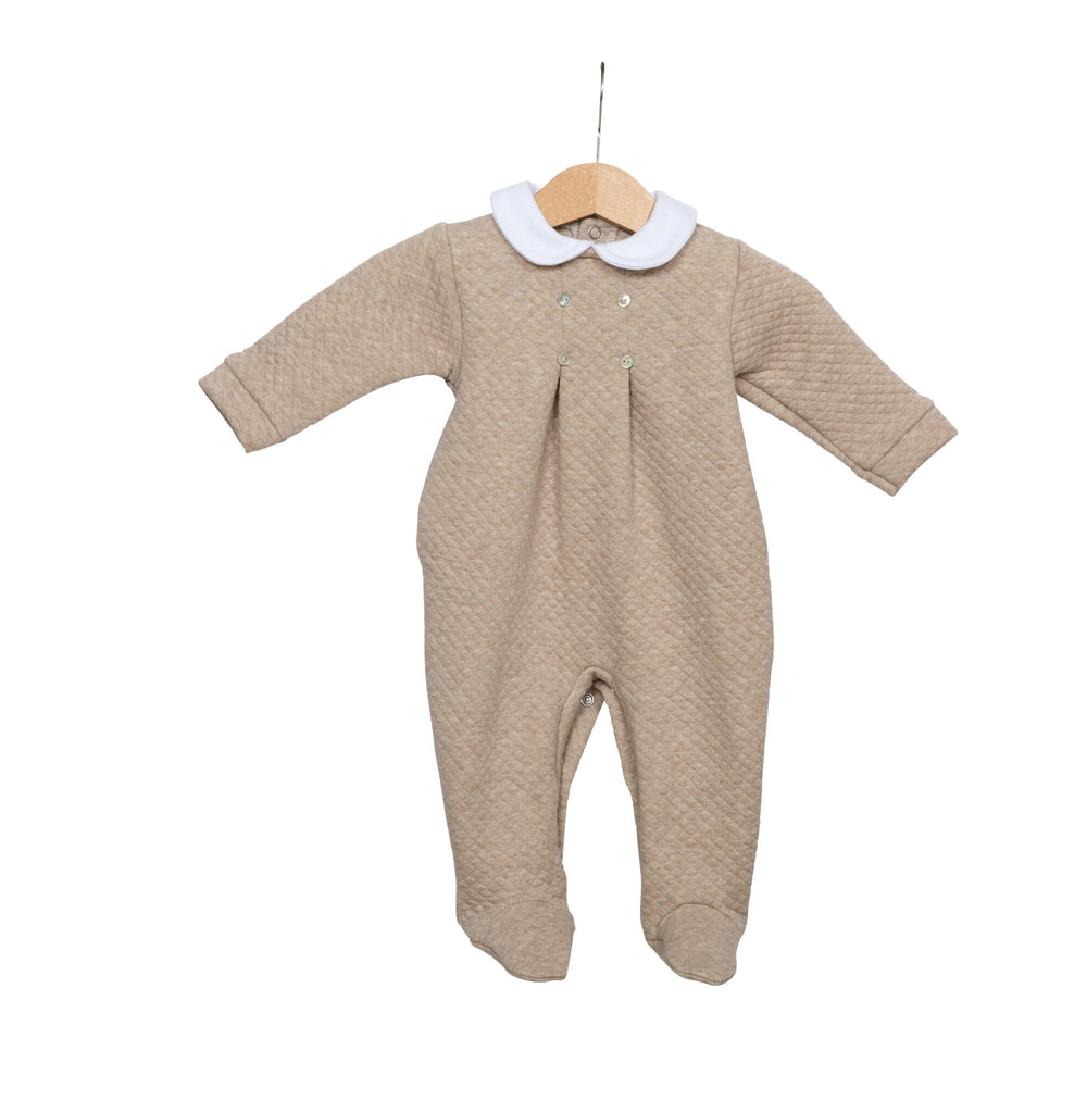 Een beige boxpakje met een wit kraagje aan een kledinghaakje