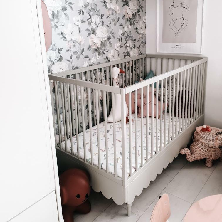 Een olijfgroen ledikantje in een babykamer