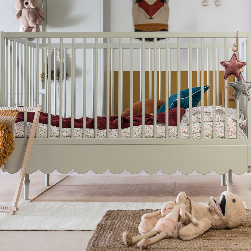 Een olijfkleurig ledikant in een babykamer